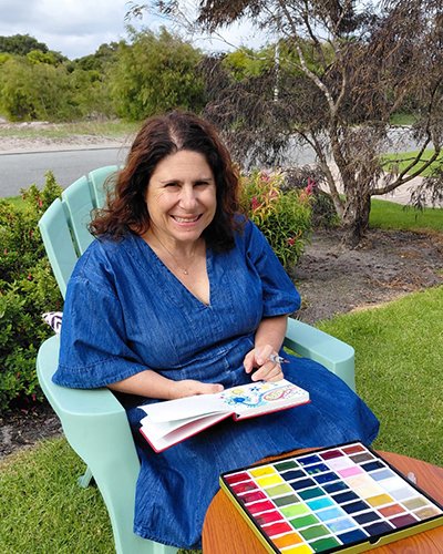 Fiona Perraula sitting in a chair and painting